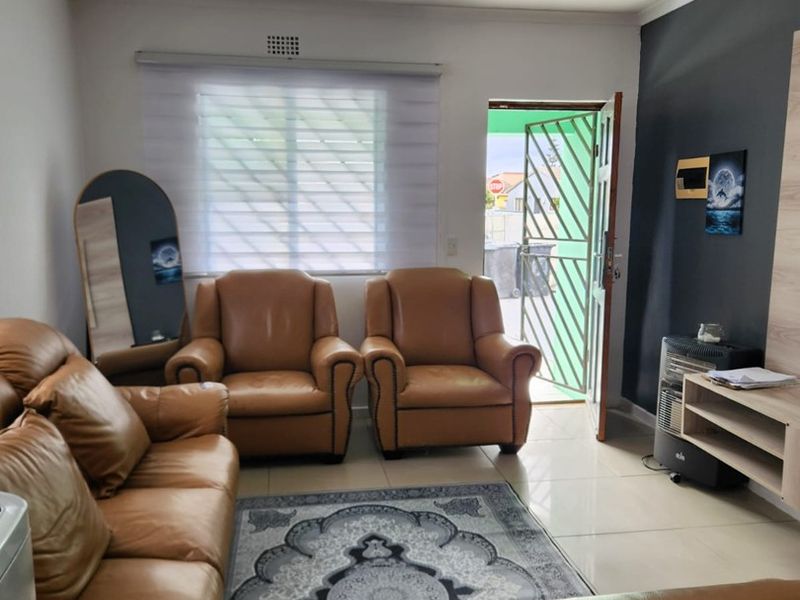 A living room featuring tiled flooring, a security gate at the entrance, and a ceiling-mounted spotlight fixture.