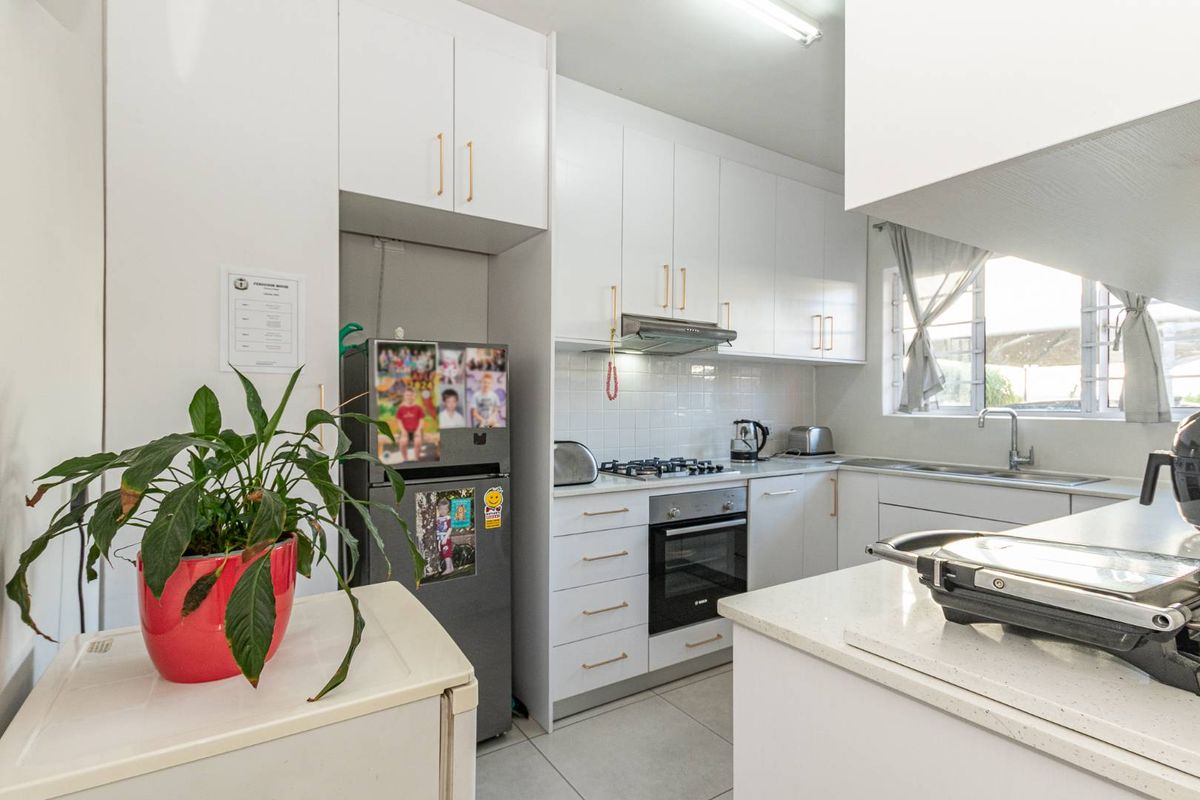 A functional kitchen featuring white cabinetry, stone countertops, a built-in oven, gas hob, and an extractor fan with tiled splashbacks.
