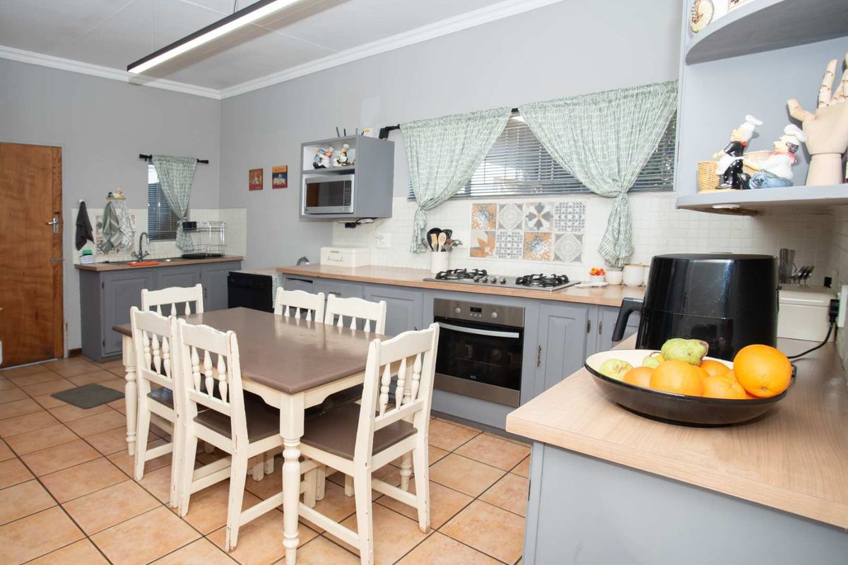 A functional kitchen featuring grey cabinetry, gas hob, built-in oven, and tiled flooring, with an integrated dining area.
