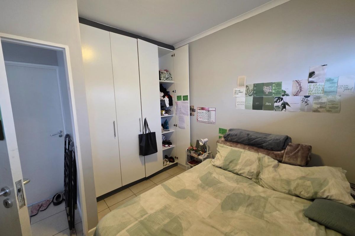A bedroom featuring built-in white cabinetry with integrated shelving and tiled flooring.