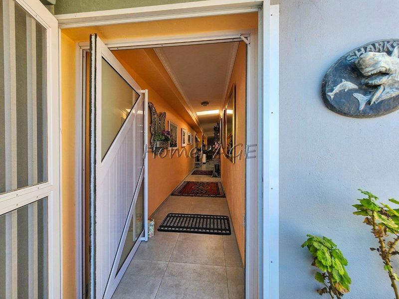 A long interior hallway featuring tiled flooring and decorative cove cornicing, providing access to the rest of the home.