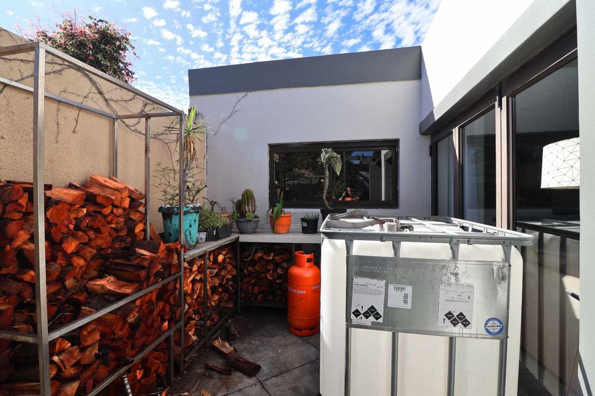 A functional outdoor utility area featuring a concrete workspace, firewood storage racks, and access to the main dwelling through sliding glass doors.