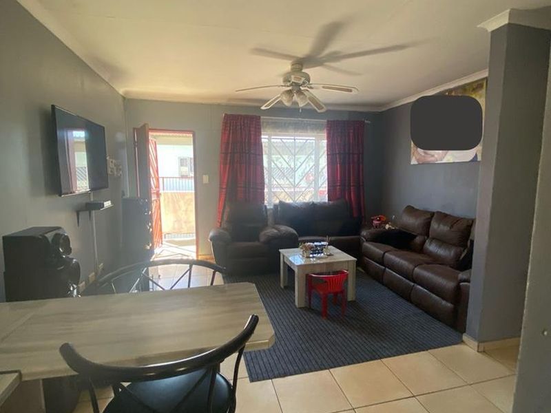 Open plan living and dining area featuring tiled flooring, a ceiling fan, and direct access to the exterior through a security gate.