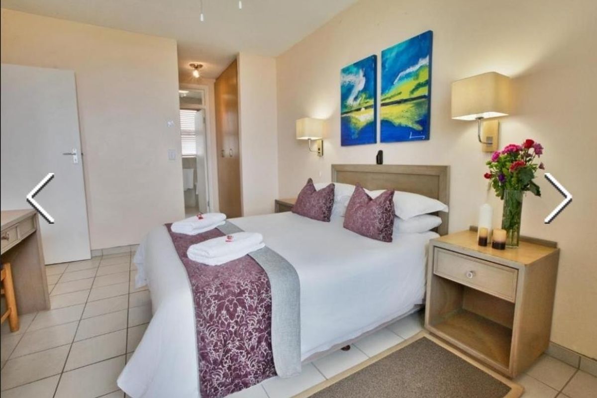 A well-lit bedroom featuring tiled flooring, built-in cupboards, and an en-suite bathroom access.
