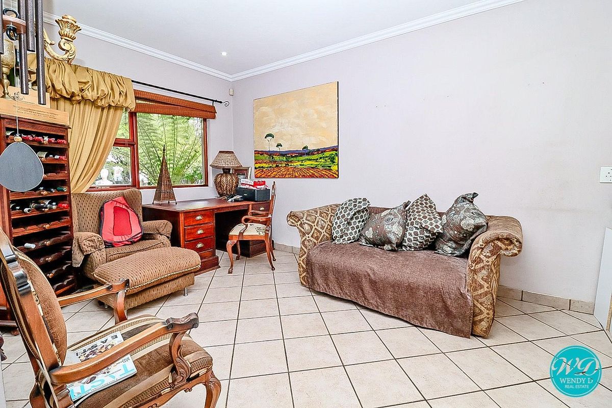 A living room featuring tiled flooring, crown molding, and large windows providing natural light.