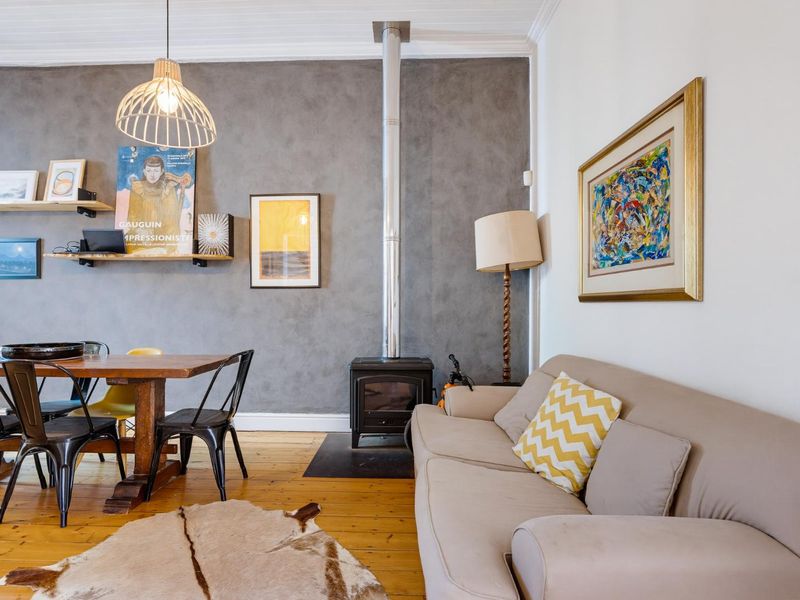 Open-plan living and dining area featuring polished timber flooring, a wood-burning stove with a flue, and a textured feature wall.