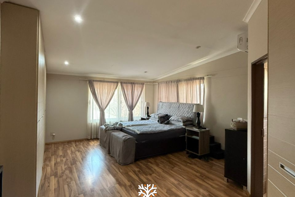 Spacious bedroom featuring wood-look laminate flooring, built-in floor-to-ceiling cabinetry, and recessed downlighting.