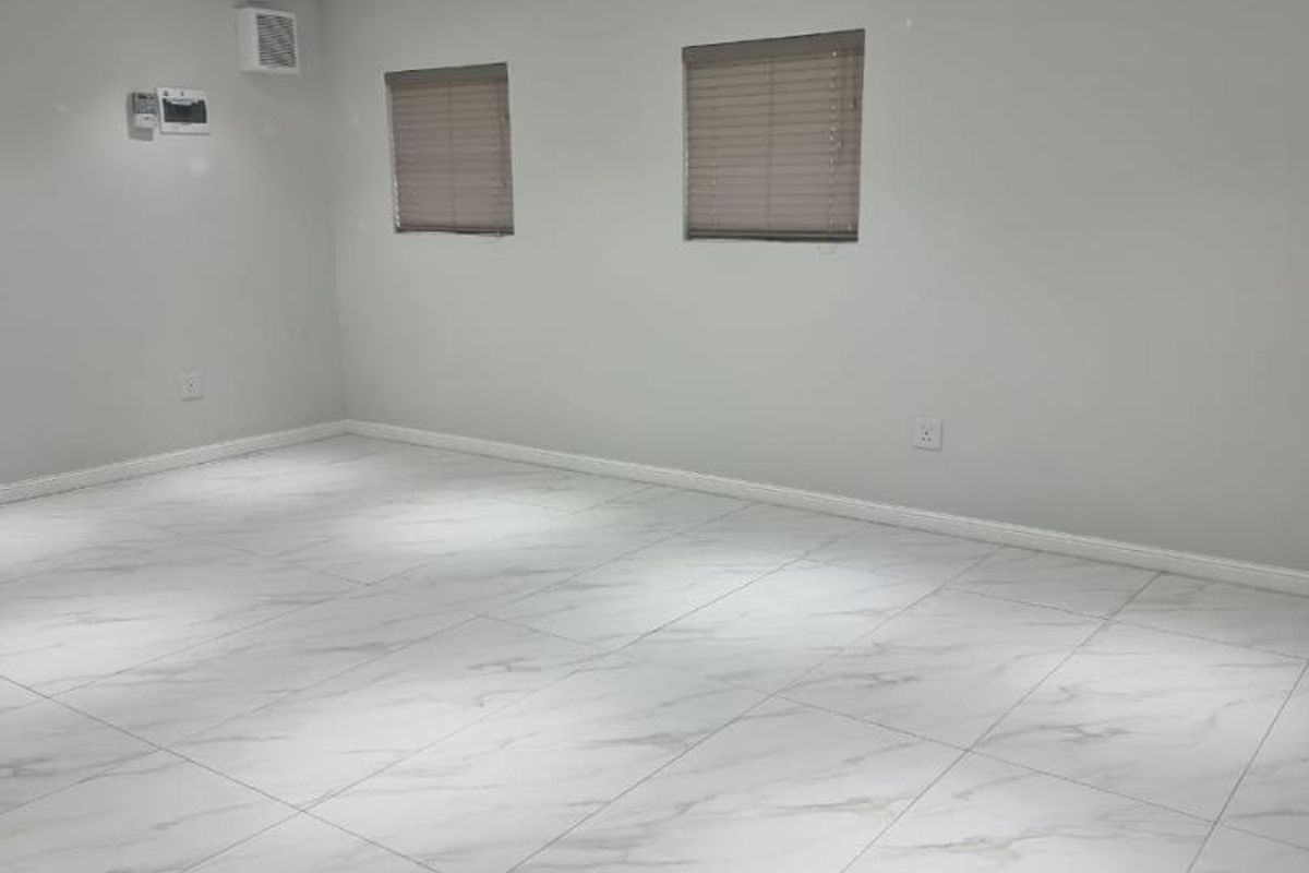 A bright, open-plan retail space featuring modern marble-look floor tiles, recessed ceiling lighting, and neutral wall finishes.