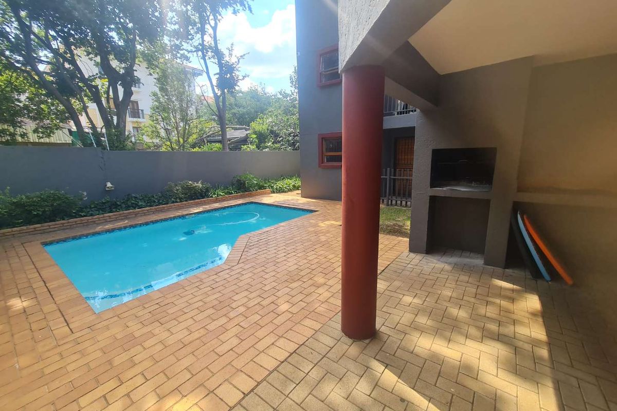 Outdoor entertainment area featuring a swimming pool, paved patio, and a built-in braai facility, perfect for relaxed outdoor living.