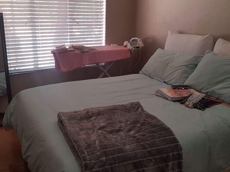 A standard bedroom featuring laminate flooring and venetian blinds, providing a functional space with natural light.