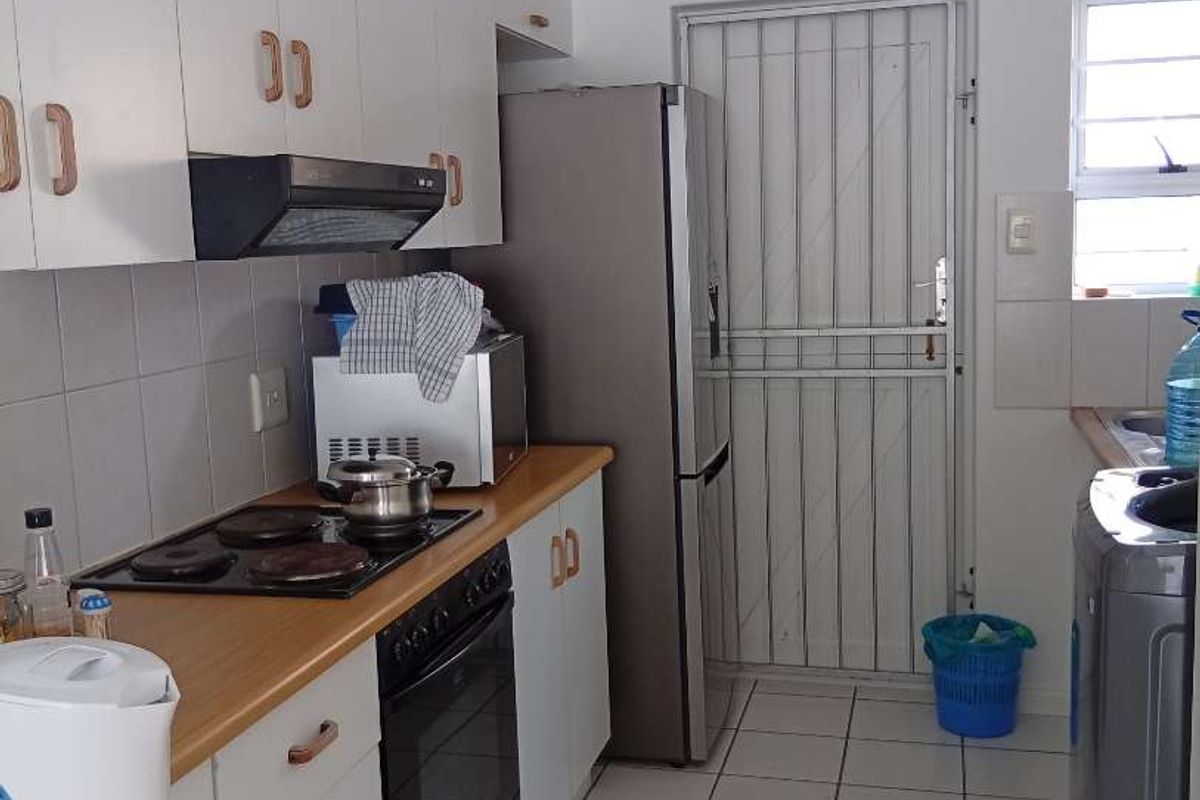 Functional kitchen featuring white cabinetry, wood-look countertops, built-in oven and hob, tiled flooring, and a secure rear access door.