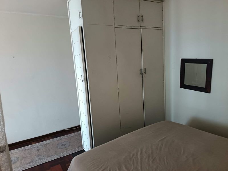 A bedroom featuring a built-in wardrobe and parquet flooring, offering a functional space with potential for cosmetic updates.