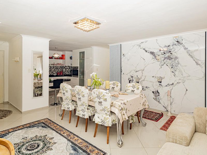 Spacious open-plan living and dining area featuring a striking marble-look feature wall, polished tiled flooring, and a modern integrated kitchen.