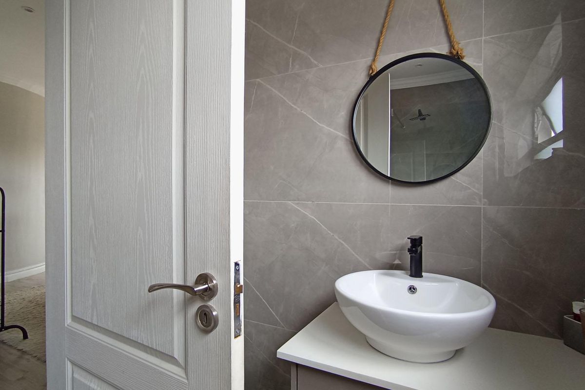 A modern bathroom featuring a contemporary vessel sink, matte black faucet, and large-format grey wall tiles.