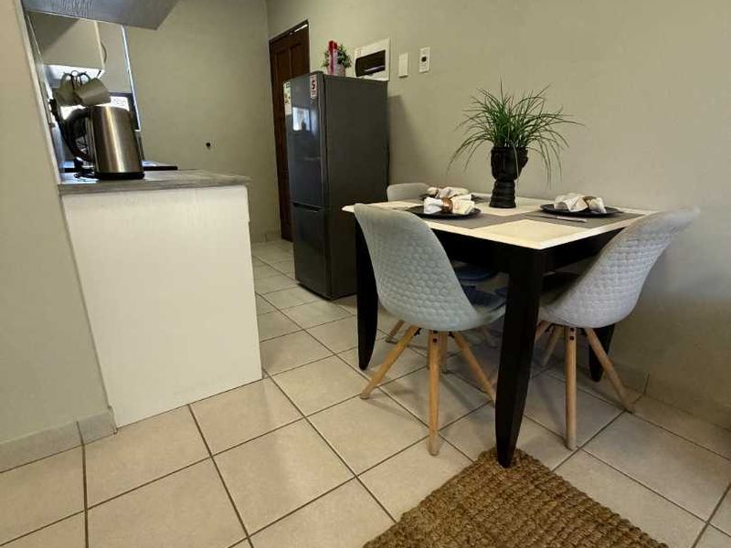 Compact open-plan kitchen and dining area featuring tiled flooring and functional cabinetry, offering a practical layout for apartment living.