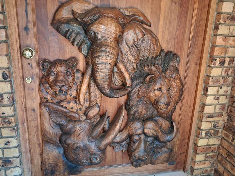 A unique, custom-carved wooden front door featuring detailed wildlife relief, set within a face brick entrance.