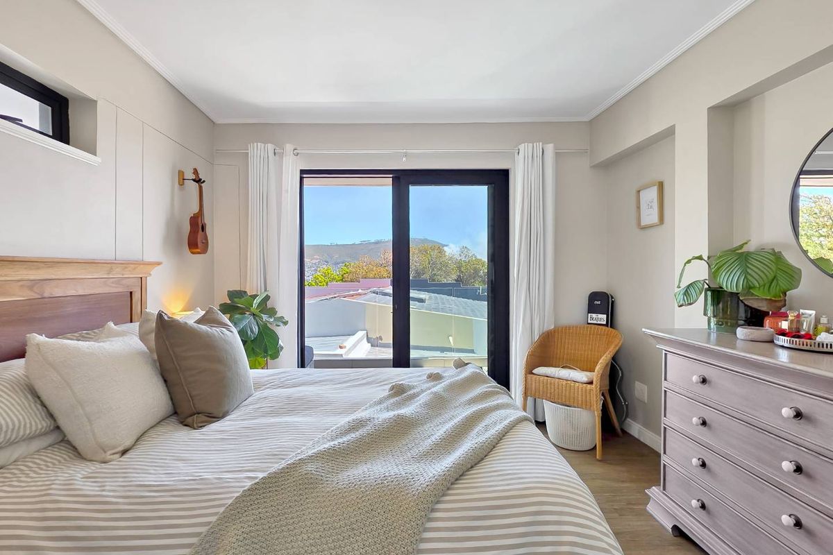 A bright and well-maintained bedroom featuring laminate flooring, a recessed wall niche, and a sliding glass door providing access to an outdoor area.