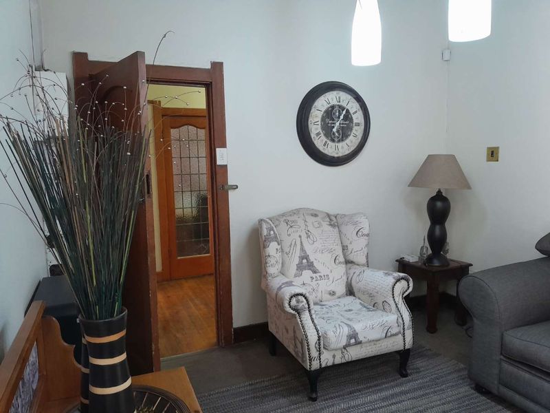 A cozy living area featuring hardwood flooring, a classic leaded glass door, and warm pendant lighting, creating a welcoming atmosphere.