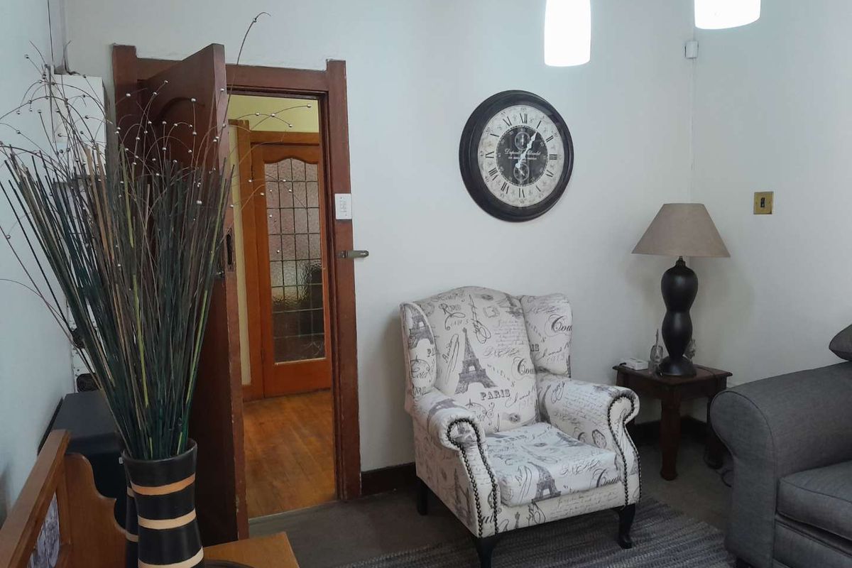 A cozy living area featuring hardwood flooring, a classic leaded glass door, and warm pendant lighting, creating a welcoming atmosphere.
