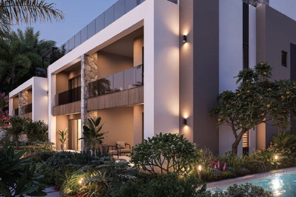 Modern apartment building exterior featuring stone accents, glass-railed balconies, and integrated lighting overlooking a landscaped pool area.