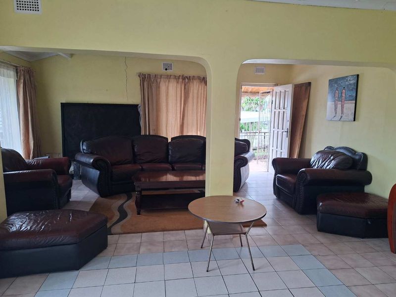 Spacious living area featuring tiled flooring and arched wall openings, with a visible structural crack requiring attention.