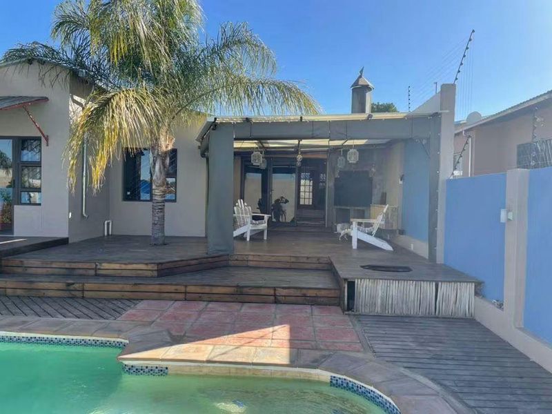 Outdoor entertainment area featuring timber decking, a covered patio with a fireplace, and direct access to a swimming pool.