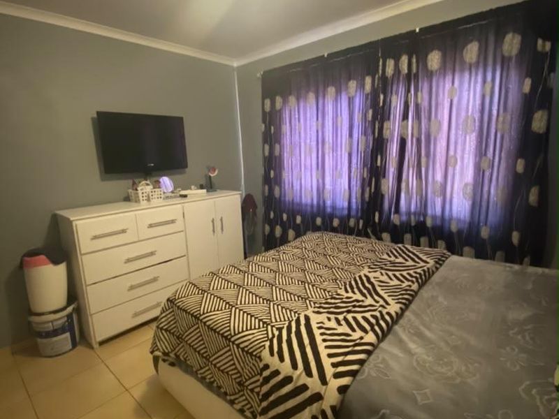 A bedroom featuring tiled flooring and neutral wall finishes, providing a functional space with natural light through the window.