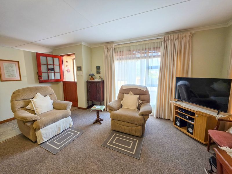 A comfortable living room featuring carpeted flooring, coving, and direct access to the exterior via a sliding glass door and a traditional stable door.