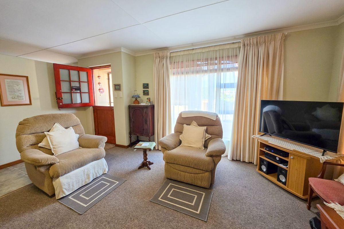 A comfortable living room featuring carpeted flooring, coving, and direct access to the exterior via a sliding glass door and a traditional stable door.
