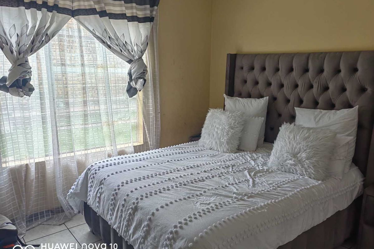 A bedroom featuring tiled flooring and a window with curtain fixtures.