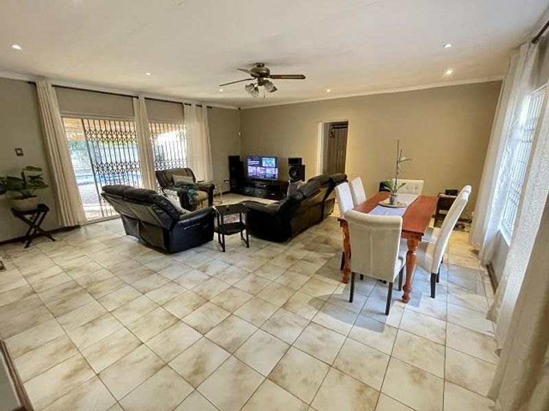 Spacious open-plan living and dining area featuring tiled flooring, a ceiling fan, and large sliding doors providing access to the outdoor area.