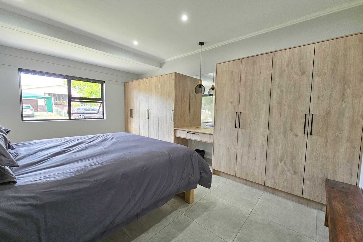 A well-maintained bedroom featuring extensive built-in light wood cabinetry, a integrated vanity area, recessed ceiling lighting, and large format floor tiles.