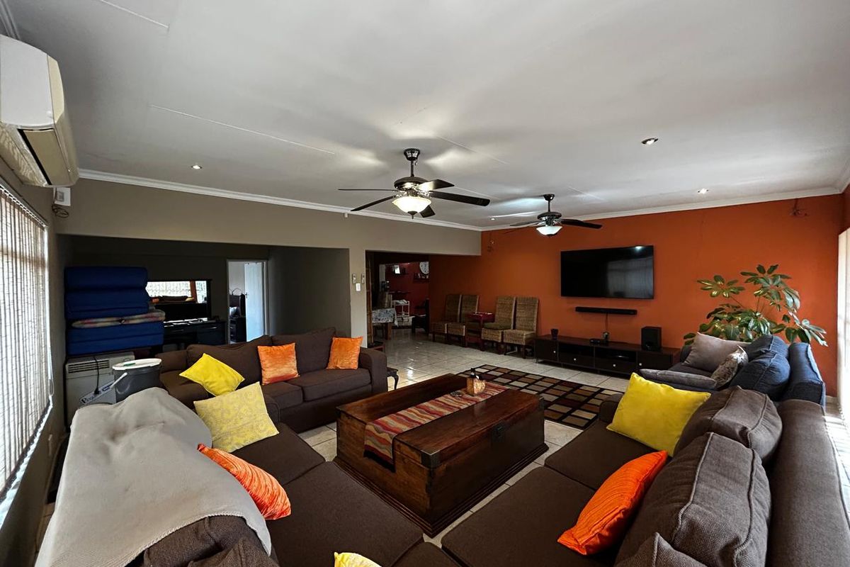 Spacious living room featuring tiled flooring, dual ceiling fans, recessed lighting, and a wall-mounted air conditioning unit.