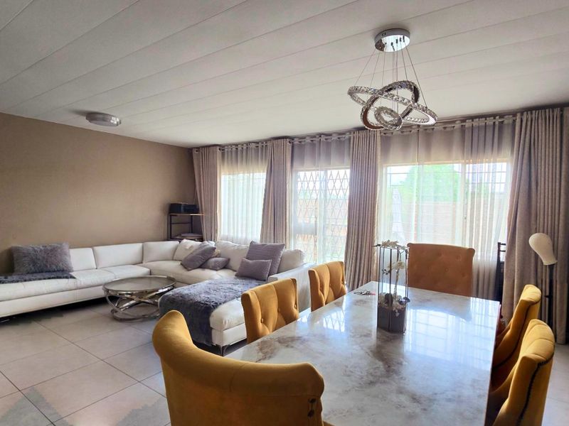 Spacious open-plan living and dining area featuring large sliding glass doors, neutral tiled flooring, and a contemporary pendant light fixture.