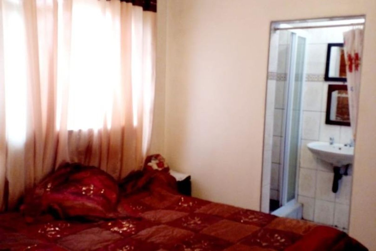 A bedroom featuring an attached en-suite bathroom with a pedestal basin and shower enclosure.