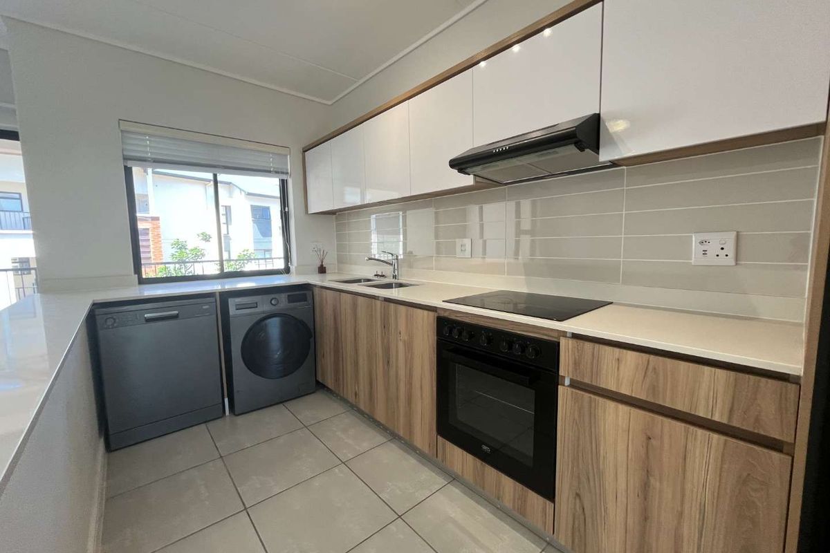 Modern kitchen featuring sleek white and wood-grain cabinetry, stone countertops, tiled backsplash, and integrated appliances including an oven, cooktop, and extractor fan.