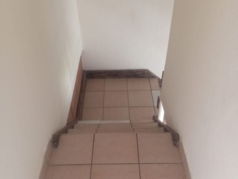 A narrow, tiled staircase area showing signs of wear on the edges and walls, requiring minor cosmetic updates.