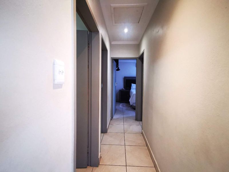 A clean, tiled hallway providing access to adjacent rooms, featuring neutral wall tones and recessed ceiling lighting.
