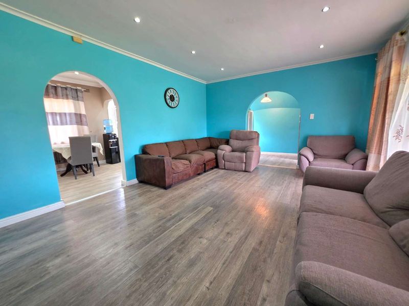 Spacious living room featuring wood-look laminate flooring, recessed downlighting, and distinctive arched doorways leading to adjacent living areas.