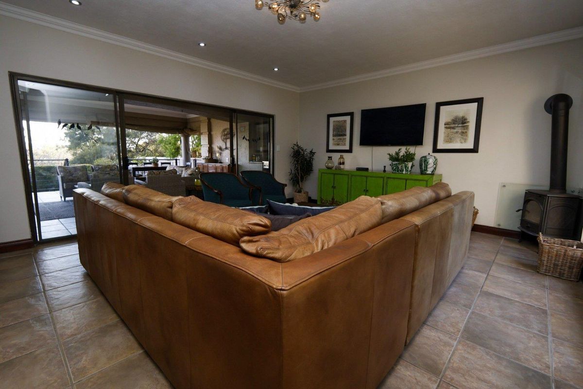 Spacious living room featuring large sliding glass doors leading to an outdoor patio, tiled flooring, and a built-in wood-burning fireplace.