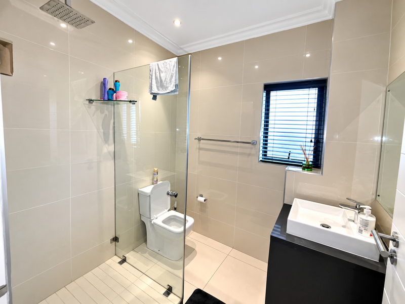 Modern bathroom featuring a walk-in shower with a rain shower head, wall-mounted toilet, and a sleek vanity with a vessel sink.