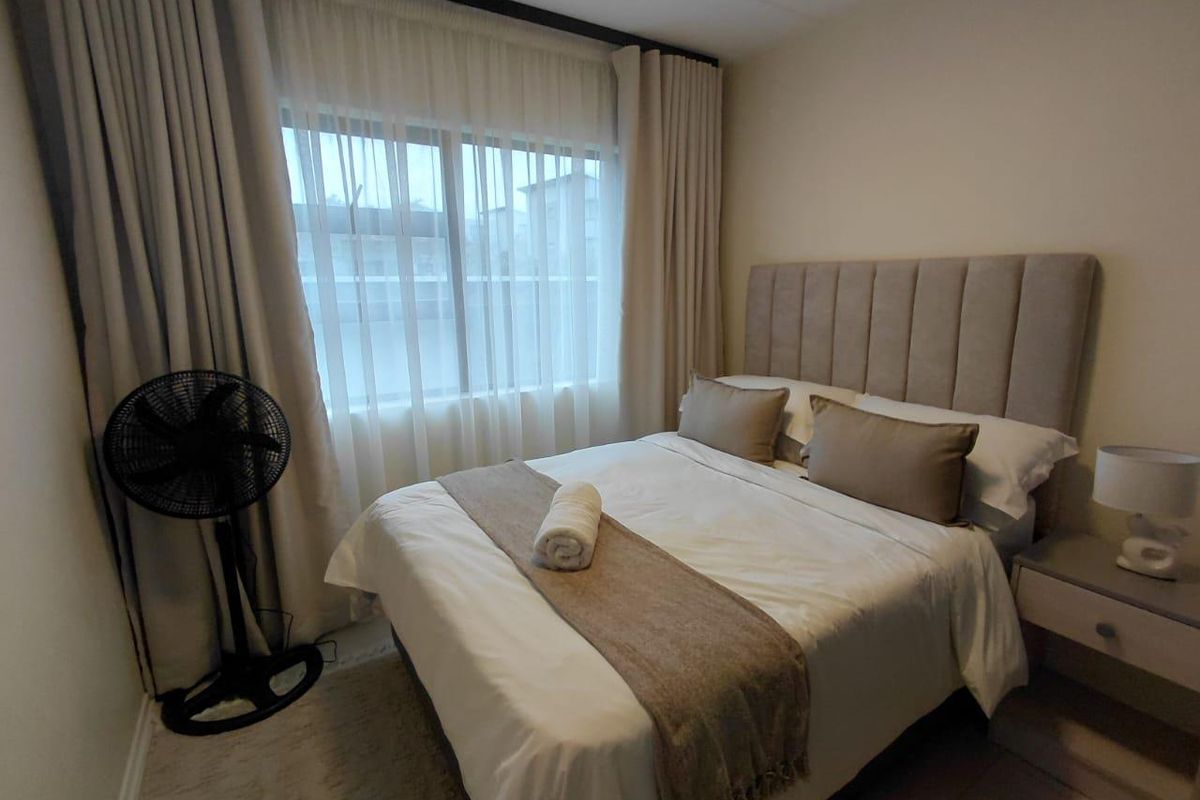 A well-maintained bedroom featuring neutral tones, soft window treatments, and a clean, modern aesthetic.