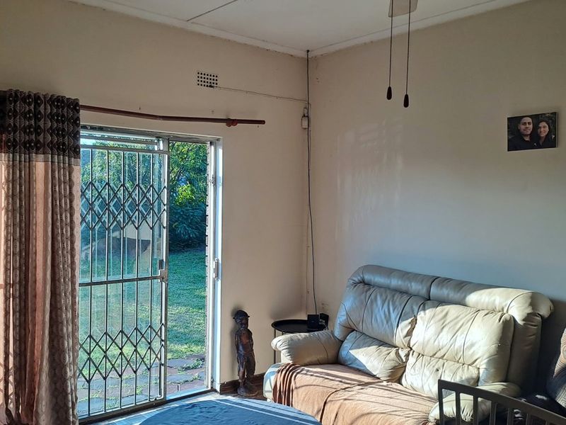 A living room featuring a ceiling fan, sliding glass door with security gate, and access to the garden area.