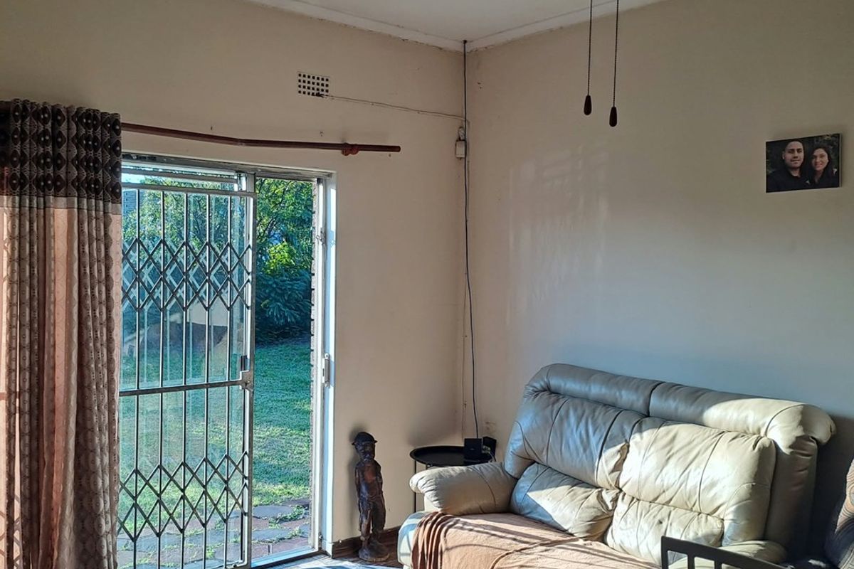 A living room featuring a ceiling fan, sliding glass door with security gate, and access to the garden area.
