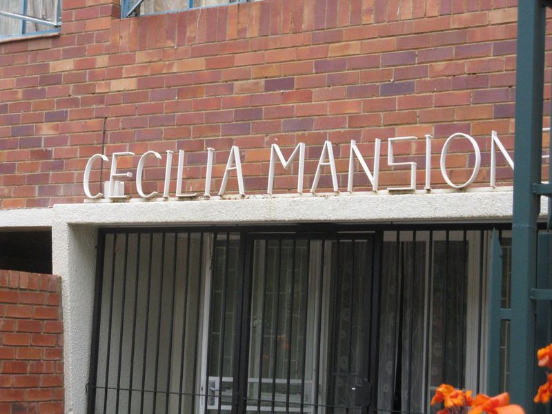 Front entrance view of Cecilia Mansion featuring a classic brick facade and secure metal gate access.