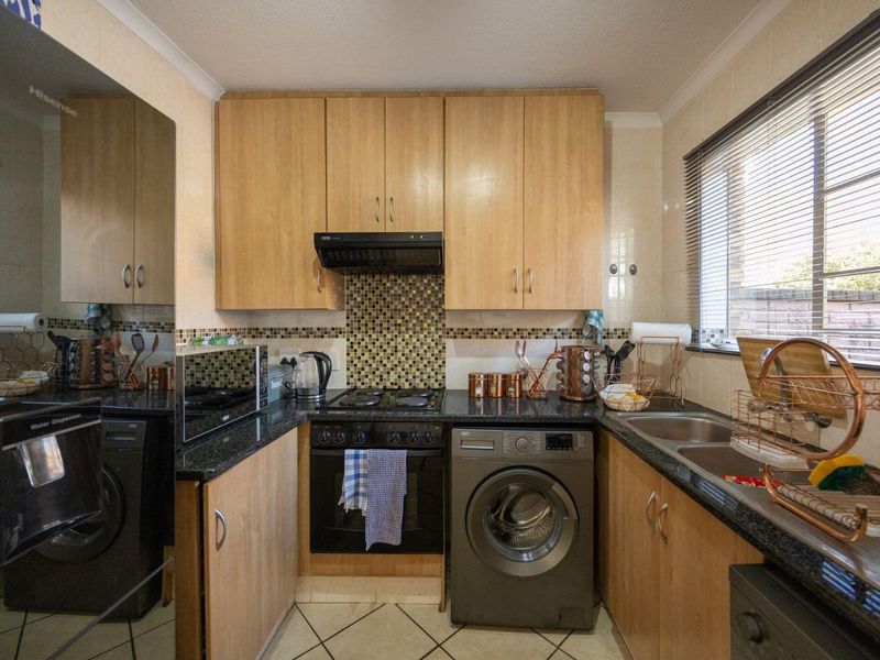 Compact kitchen featuring light wood cabinetry, granite countertops, mosaic tile backsplash, and integrated appliances including an oven, hob, and extractor fan.