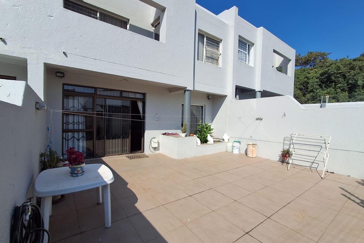 A spacious paved rear patio area featuring a sliding door entrance, built-in planter box, and direct access to the townhouse exterior.