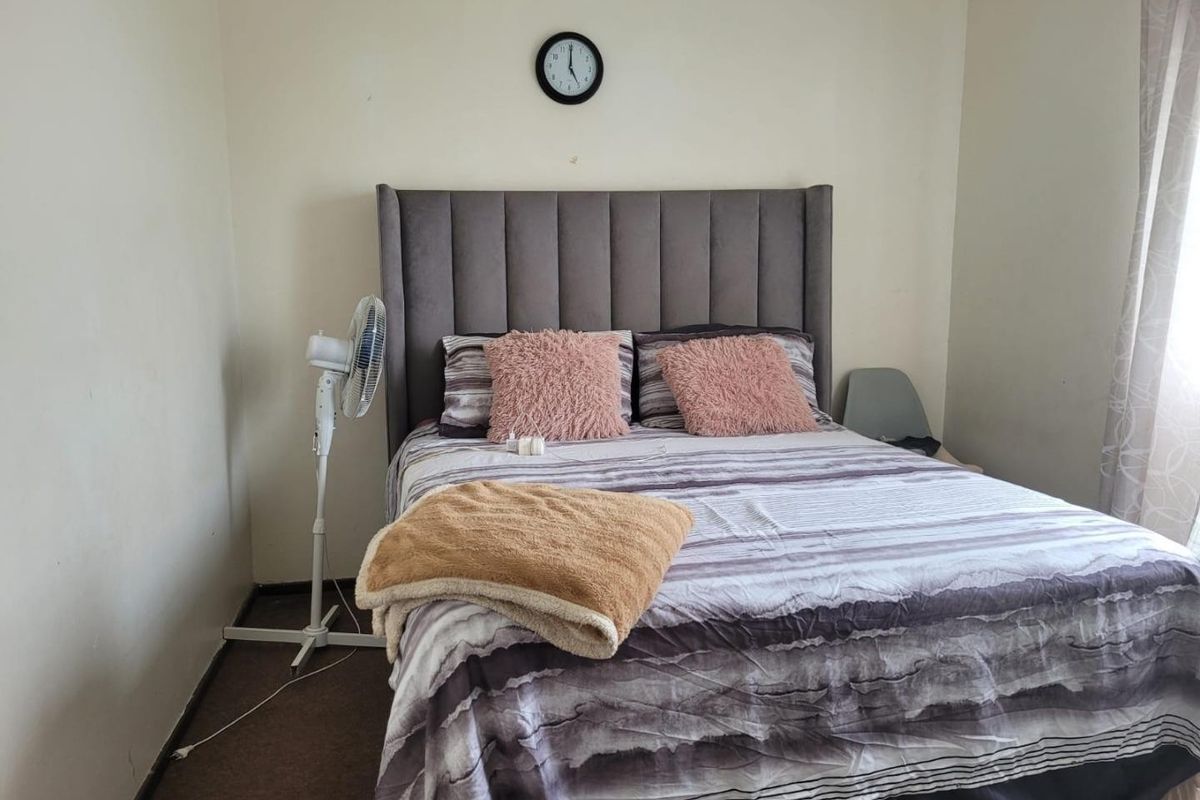 A standard bedroom featuring neutral wall finishes and carpeted flooring, providing a functional space for rest.