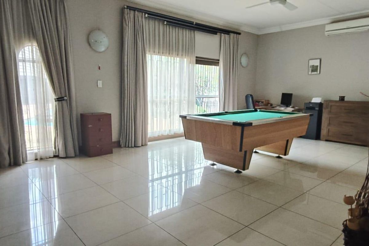 Spacious living area featuring large format floor tiles, wall-mounted air conditioning unit, and sliding glass doors providing access to the outdoor area.
