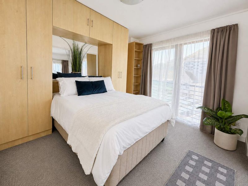 A well-maintained bedroom featuring extensive built-in cabinetry, integrated shelving, and a large sliding glass door providing natural light and access to the exterior.